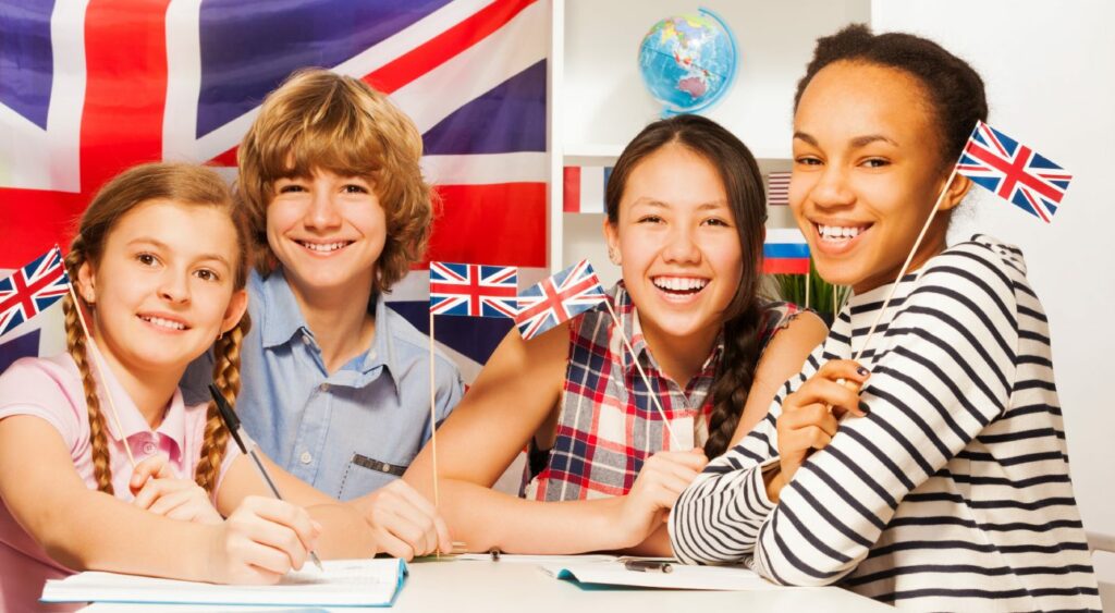 AWO Forchheim. - Vier junge Menschen stehen an einem Tisch vor einer englischen Flagge.