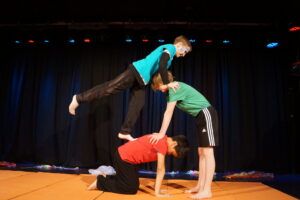 Drei Schüler turnen auf einer Bühne und bilden eine Formation