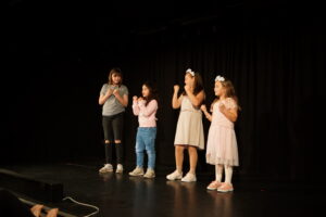 Vier Mädchen stehen auf einer Bühne und applaudieren