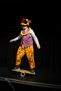 Ein Schüler, verkleidet als Clown, balanciert auf einem Balancebrett