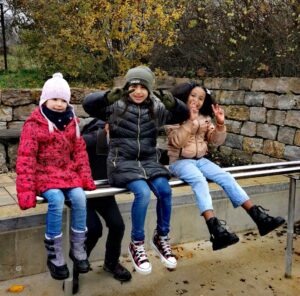 Drei Mädchen sitzen auf einer Mauer
